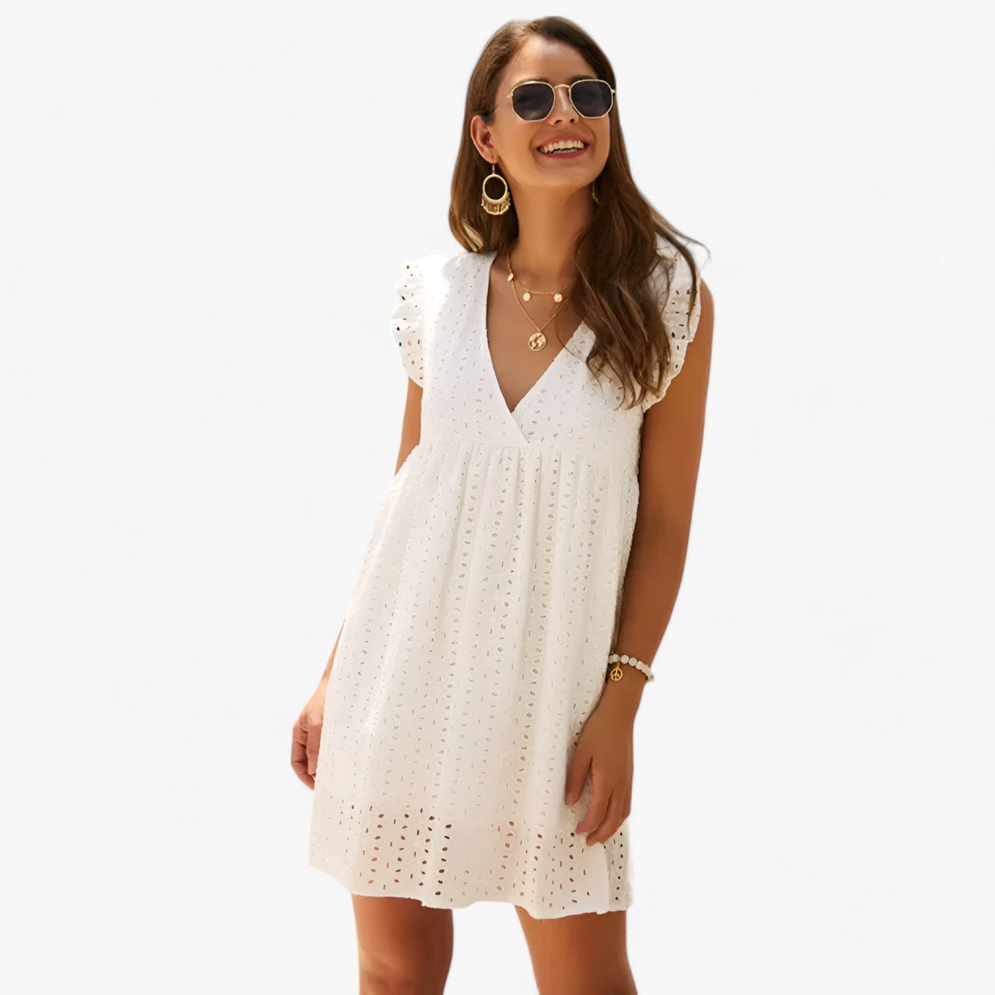 Cream - A woman smiling in a black eyelet mini dress with flutter sleeves, a deep V-neckline, and an empire waist, set against a clean white background.