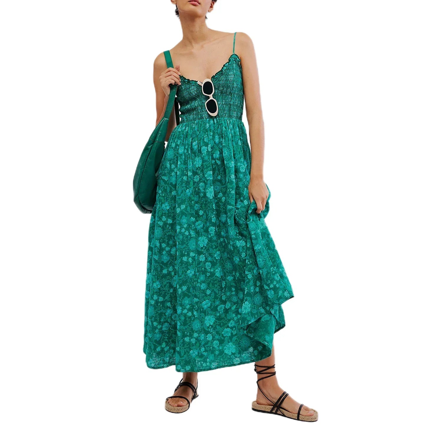 Floral Cyan - A woman wearing a pink and white floral print maxi dress featuring a smocked bodice, ruffled neckline, and thin straps, standing against a rustic stone wall.