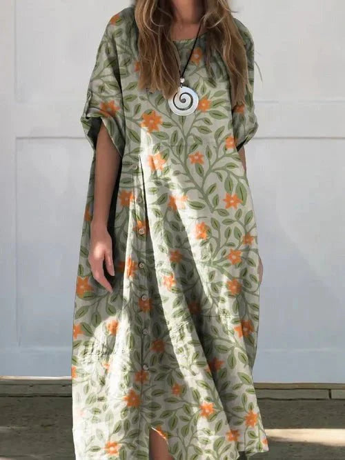 Multicolor-3 - A woman wearing a loose-fitting, taupe-colored textured linen maxi dress with short cuffed sleeves, a round neck, and a decorative side button placket down the front-right side.