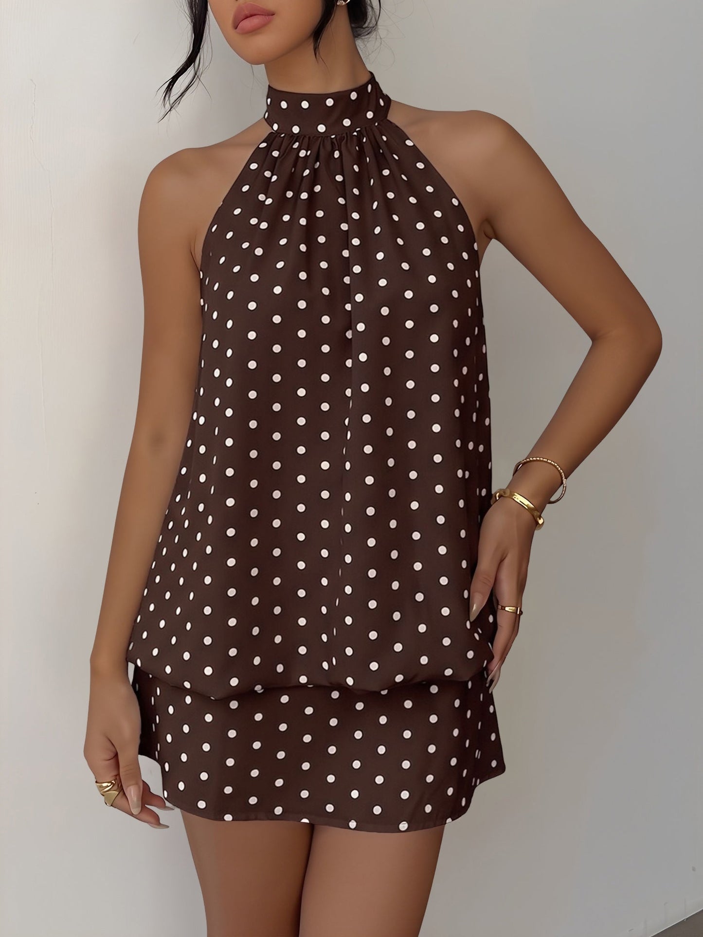 Coffee - Woman wearing a sleeveless polka dot halter mini dress with a tiered drape against a plain background