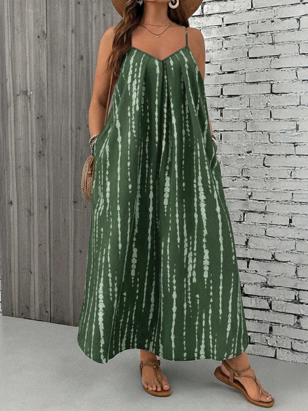 Dark Green - A woman stands on a sandy beach wearing a sleeveless maxi dress with a bold green, pink, and yellow tropical leaf print, featuring spaghetti straps and side pockets.