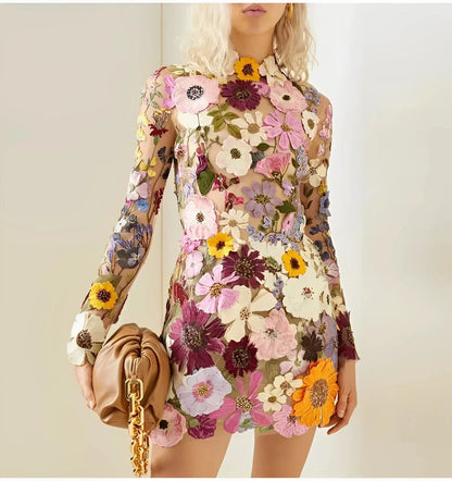 Pink - Sheer long-sleeve mini dress featuring a high neckline and dense, multi-colored 3D floral appliqués over a neutral tulle base.