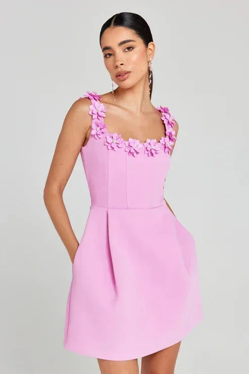 Pink - Sleeveless structured pink mini dress featuring a square neckline adorned with 3D floral appliqués, a tailored bodice with vertical seams, and a pleated A-line skirt with side pockets.