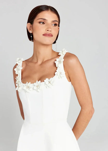 Black - Black structured crepe mini dress featuring a tailored bodice, A-line skirt with side pockets, and contrasting white 3D floral appliqués along the square neckline and shoulder straps.