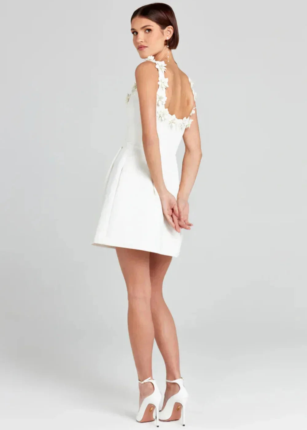 Black - Black structured crepe mini dress featuring a tailored bodice, A-line skirt with side pockets, and contrasting white 3D floral appliqués along the square neckline and shoulder straps.