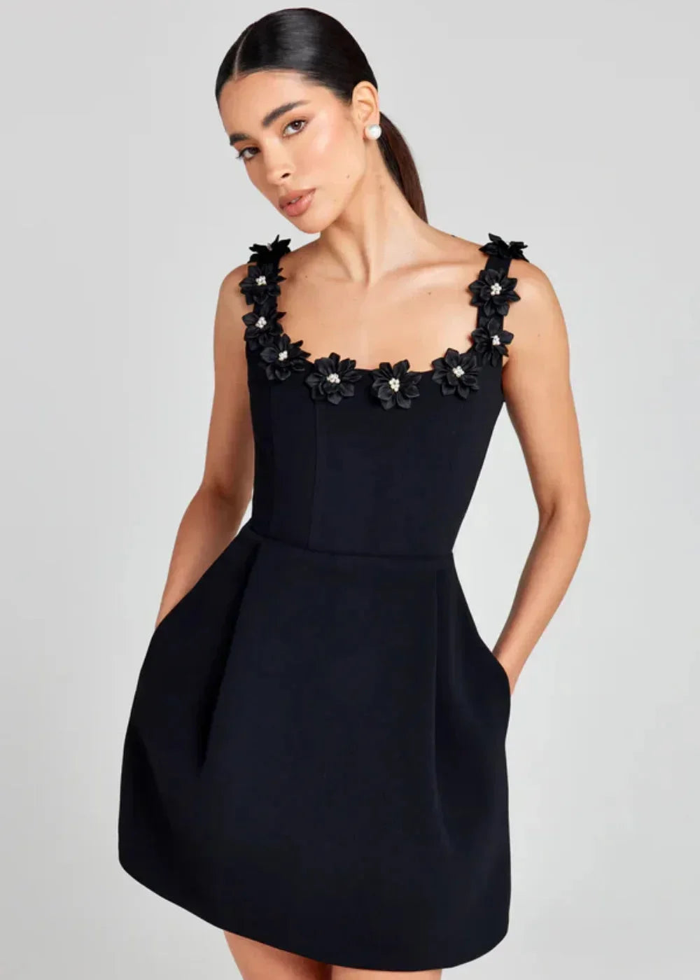 Black - Black structured crepe mini dress featuring a tailored bodice, A-line skirt with side pockets, and contrasting white 3D floral appliqués along the square neckline and shoulder straps.