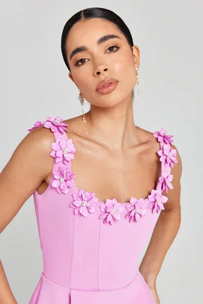 Pink - Sleeveless structured pink mini dress featuring a square neckline adorned with 3D floral appliqués, a tailored bodice with vertical seams, and a pleated A-line skirt with side pockets.