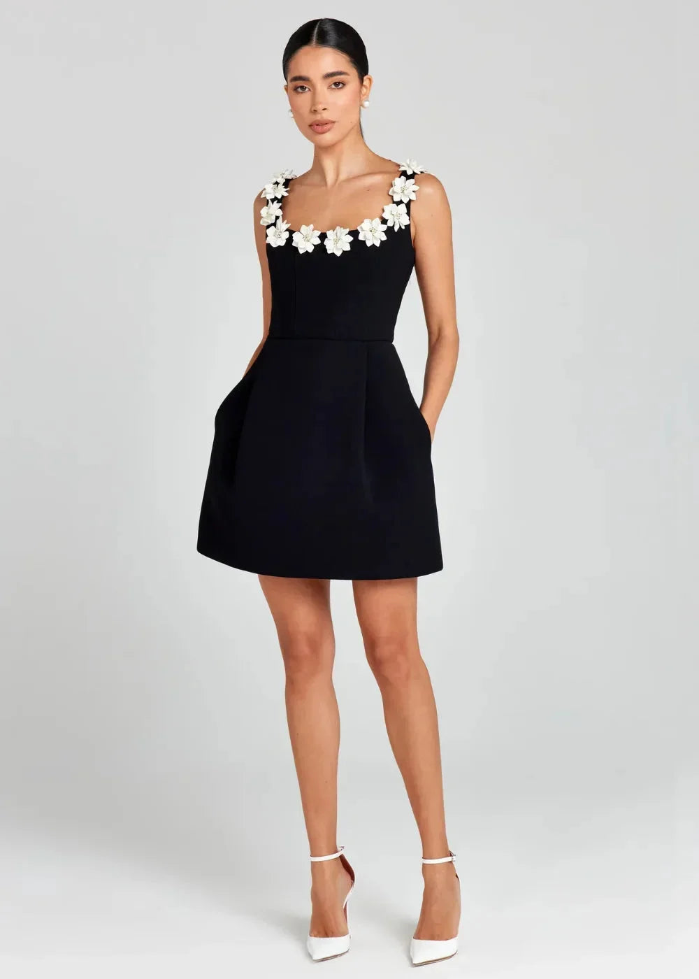 Black - Black structured crepe mini dress featuring a tailored bodice, A-line skirt with side pockets, and contrasting white 3D floral appliqués along the square neckline and shoulder straps.