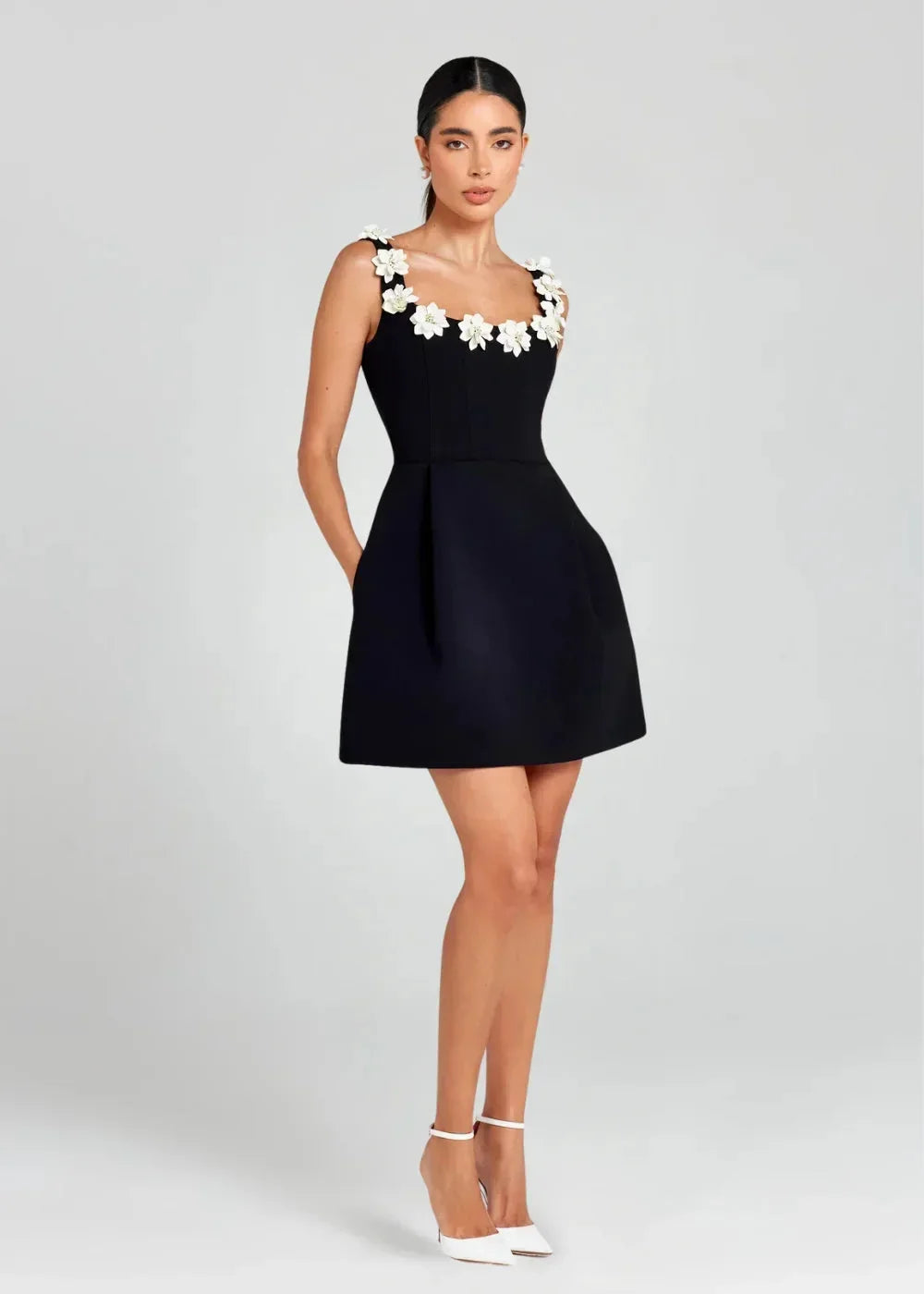 Black - Black structured crepe mini dress featuring a tailored bodice, A-line skirt with side pockets, and contrasting white 3D floral appliqués along the square neckline and shoulder straps.