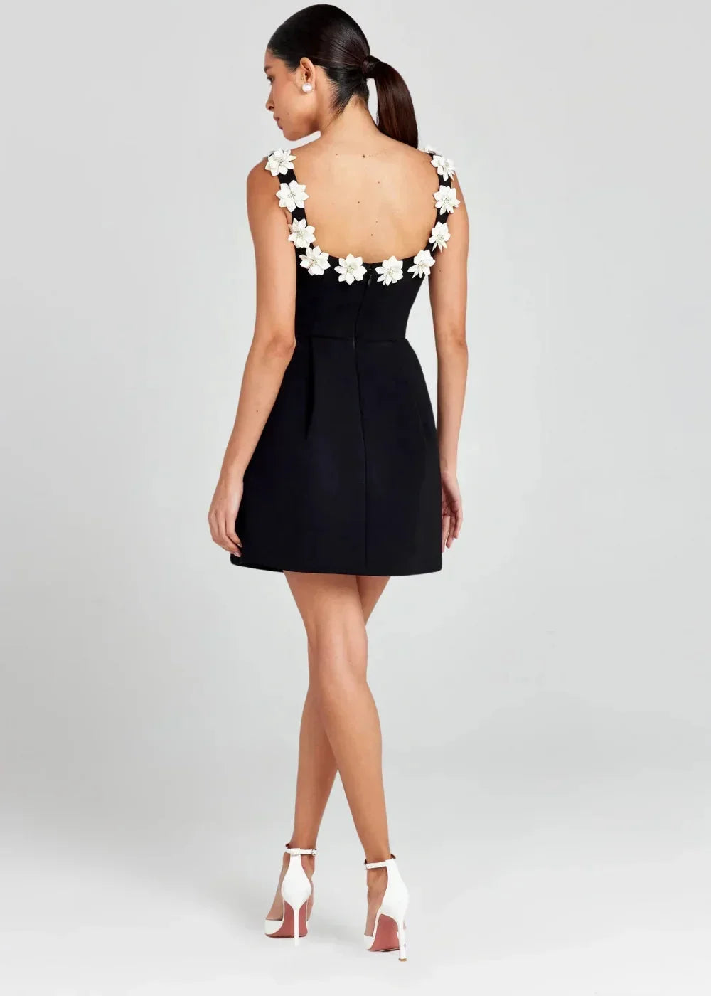 Black - Black structured crepe mini dress featuring a tailored bodice, A-line skirt with side pockets, and contrasting white 3D floral appliqués along the square neckline and shoulder straps.