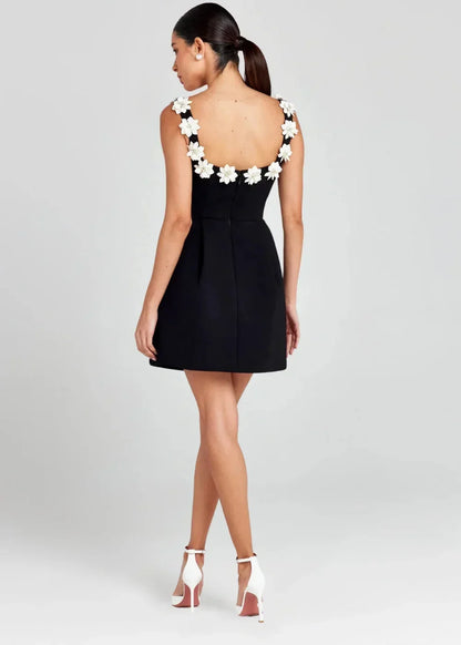Black - Black structured crepe mini dress featuring a tailored bodice, A-line skirt with side pockets, and contrasting white 3D floral appliqués along the square neckline and shoulder straps.