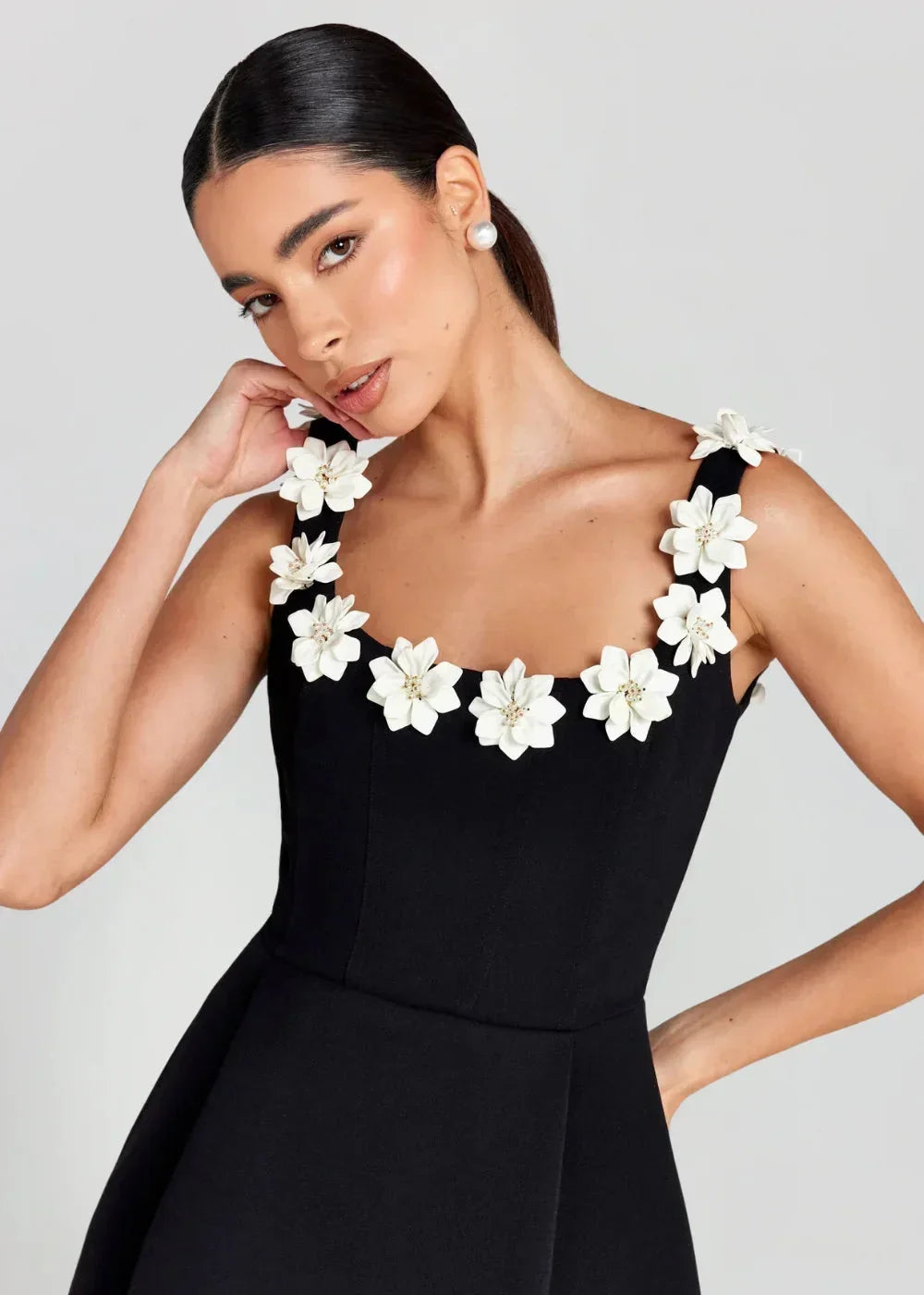 Black - Black structured crepe mini dress featuring a tailored bodice, A-line skirt with side pockets, and contrasting white 3D floral appliqués along the square neckline and shoulder straps.