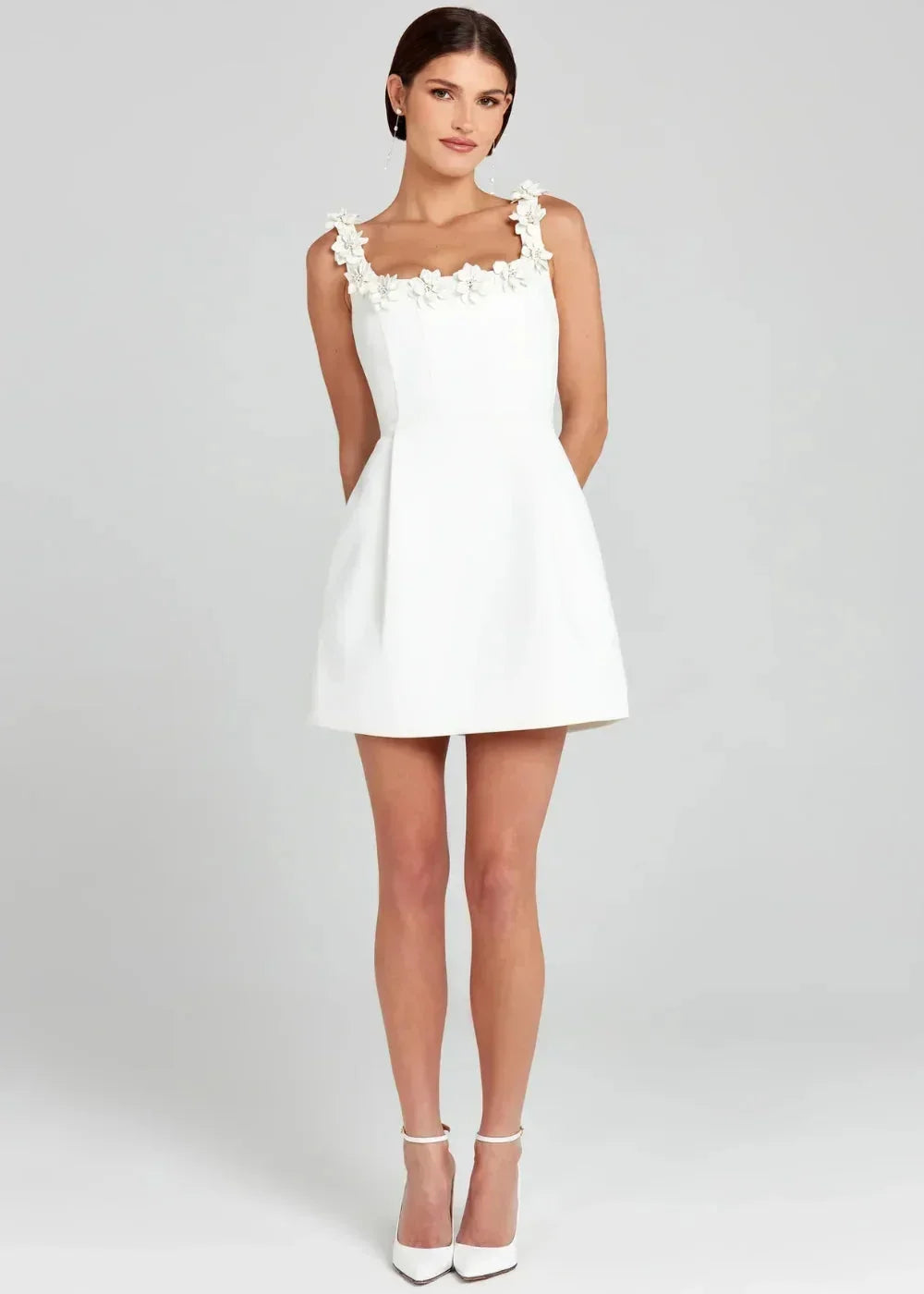 Black - Black structured crepe mini dress featuring a tailored bodice, A-line skirt with side pockets, and contrasting white 3D floral appliqués along the square neckline and shoulder straps.