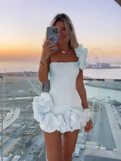 White - White one-shoulder mini dress featuring a fitted bodice and oversized 3D rosette details on the shoulder and hem.