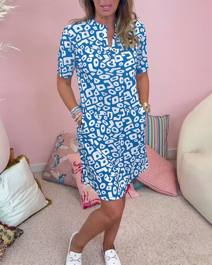 Blue - A woman wearing a black and white abstract geometric print shift dress with short sleeves, a split neckline, and side pockets.