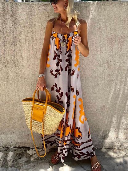 Multicolor - A woman wearing a floor-length sleeveless maxi dress with a bold orange and brown abstract leaf print on a light grey background, holding a woven straw tote bag.