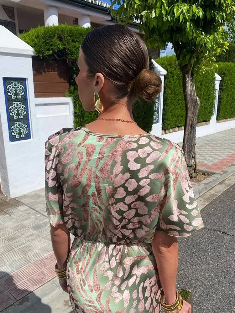 Green - Woman wearing an abstract green and pink animal print satin midi dress with a plunging neckline and twist-front waist detail.
