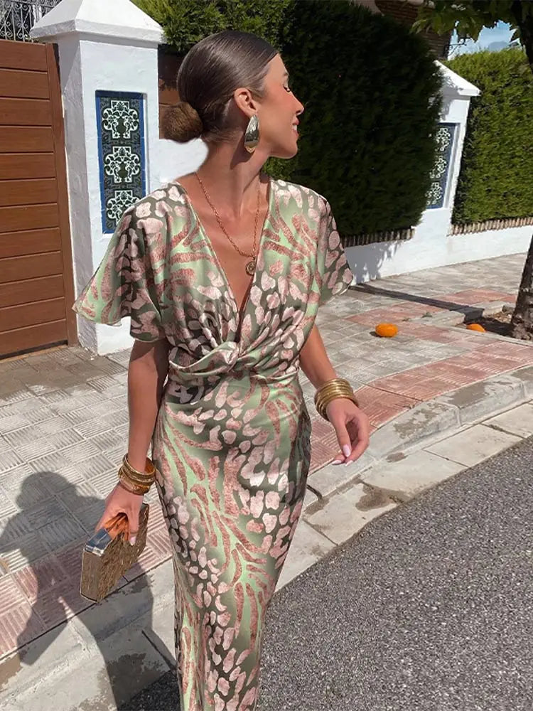 Green - Woman wearing an abstract green and pink animal print satin midi dress with a plunging neckline and twist-front waist detail.