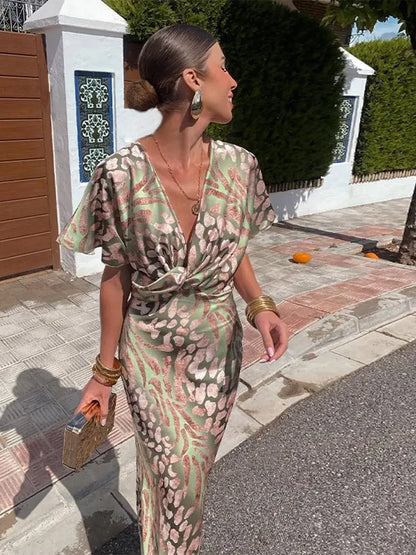 Green - Woman wearing an abstract green and pink animal print satin midi dress with a plunging neckline and twist-front waist detail.