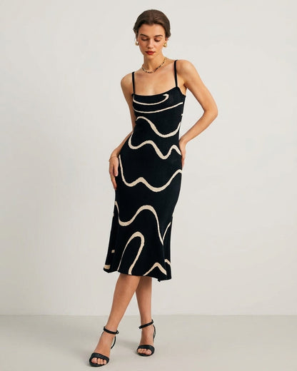 Black - A woman wearing a black knit midi dress featuring a cream abstract wave pattern, thin spaghetti straps, and a square neckline.