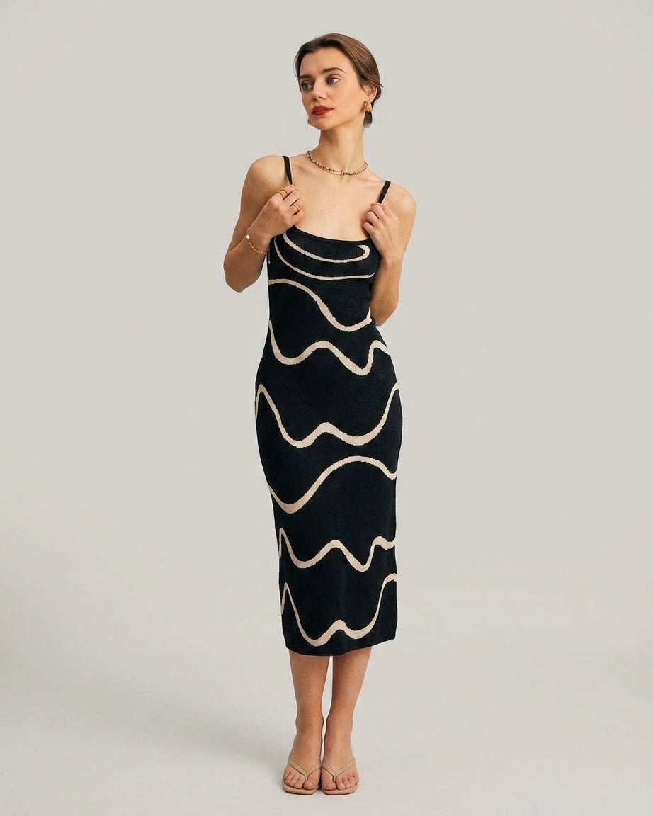 Black - A woman wearing a black knit midi dress featuring a cream abstract wave pattern, thin spaghetti straps, and a square neckline.