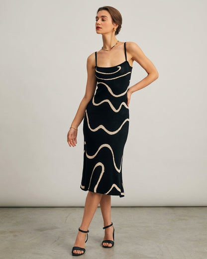 Black - A woman wearing a black knit midi dress featuring a cream abstract wave pattern, thin spaghetti straps, and a square neckline.