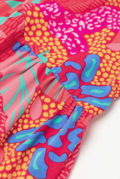 rose - Woman wearing a bright pink abstract botanical print mini dress with a v-neckline, long balloon sleeves, and a tiered babydoll skirt.