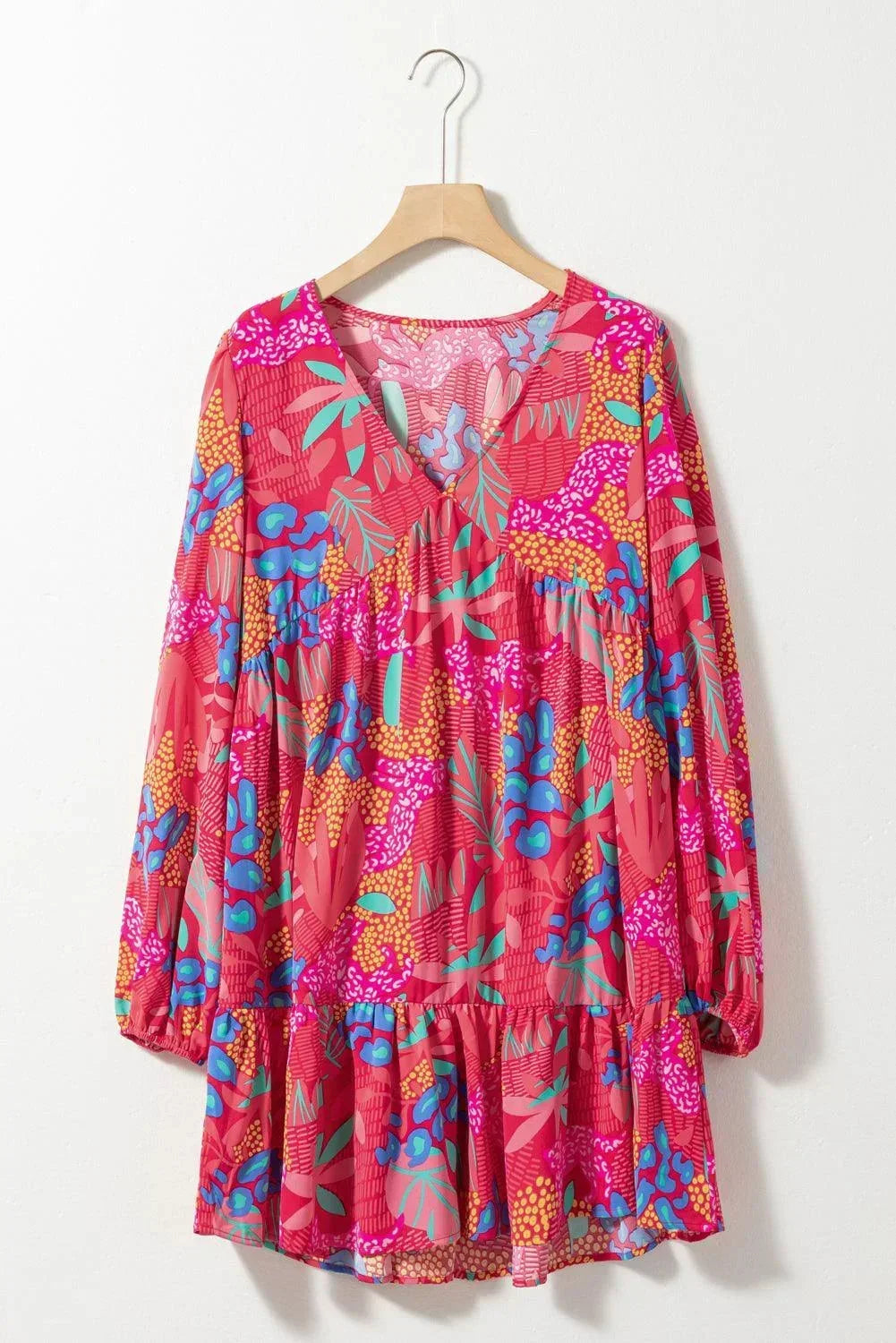 rose - Woman wearing a bright pink abstract botanical print mini dress with a v-neckline, long balloon sleeves, and a tiered babydoll skirt.