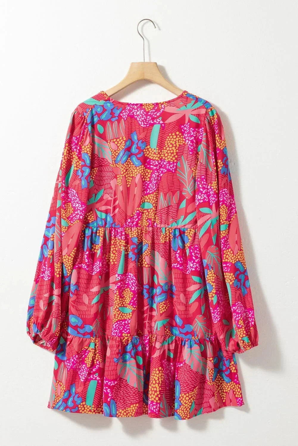 rose - Woman wearing a bright pink abstract botanical print mini dress with a v-neckline, long balloon sleeves, and a tiered babydoll skirt.