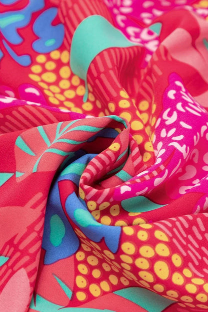 rose - Woman wearing a bright pink abstract botanical print mini dress with a v-neckline, long balloon sleeves, and a tiered babydoll skirt.