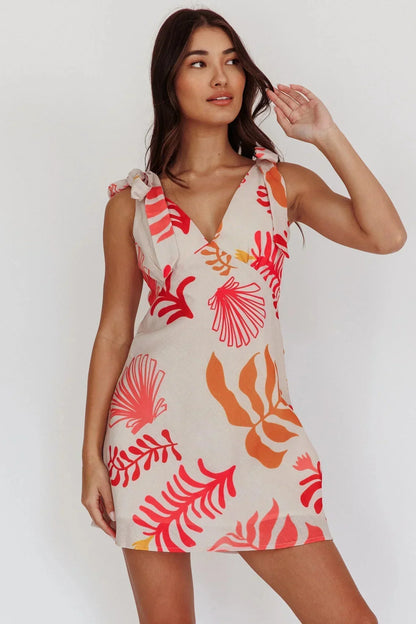 Sleeveless linen mini dress with a large-scale red and orange botanical print, featuring a V-neckline and tie-shoulder straps.