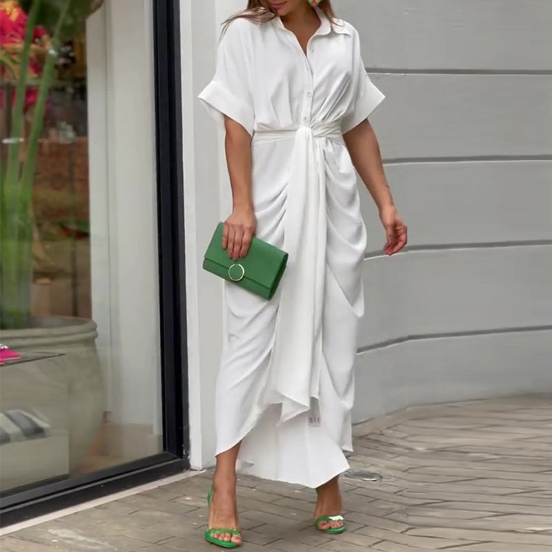 White - A woman wearing a green and cream botanical print midi shirt dress with a button-down front, belted waist, and draped skirt detail.