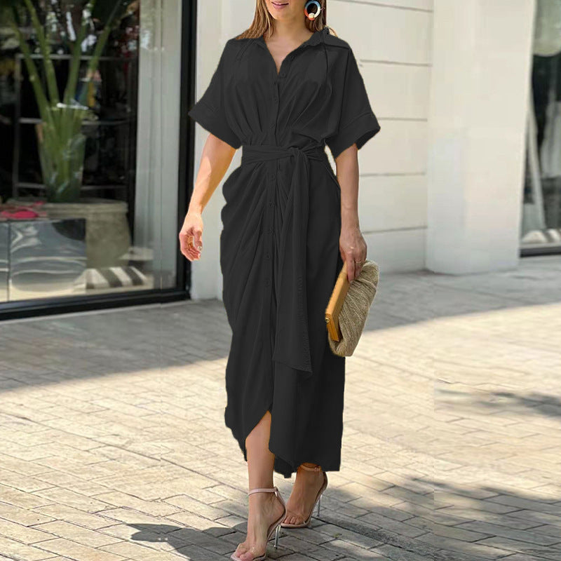 Black - A woman wearing a green and cream botanical print midi shirt dress with a button-down front, belted waist, and draped skirt detail.