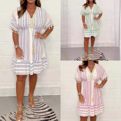 Lavender White - A woman wearing a white mini dress with blue chevron and geometric prints, featuring a V-neckline with tassel ties, flutter sleeves with tassel trim, and an empire waist.