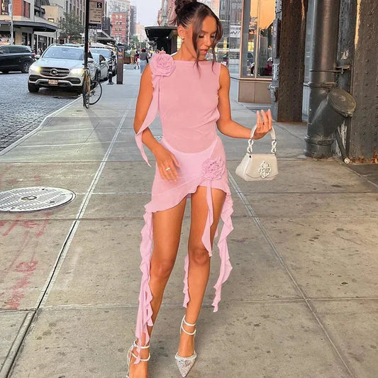 Sheer chiffon mini dress featuring a high neckline, 3D rosette appliqués on the shoulder and hip, and cascading ruffled trailing sashes with an asymmetrical hem.