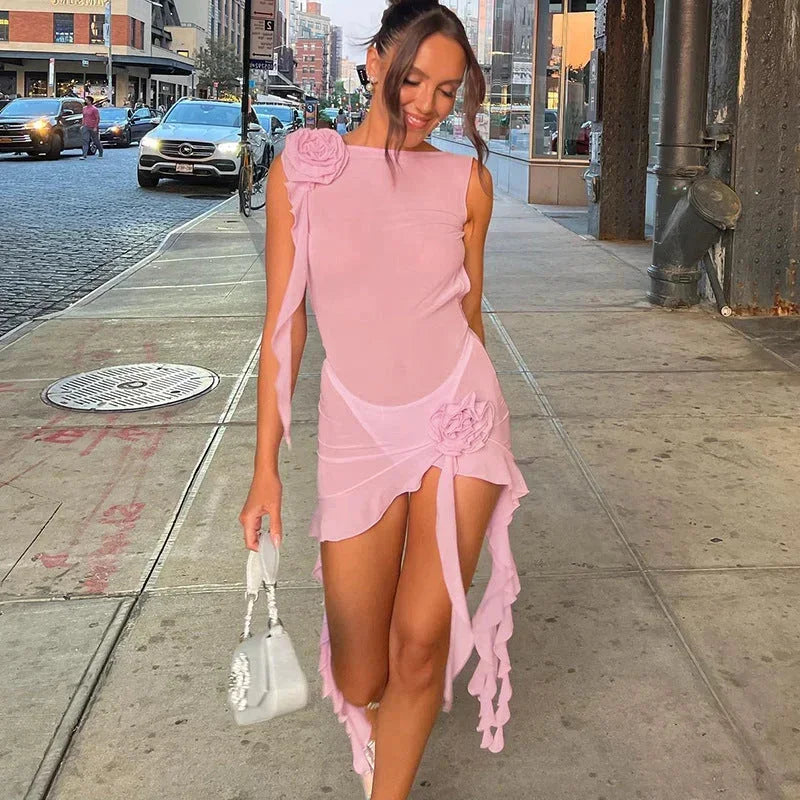 Sheer chiffon mini dress featuring a high neckline, 3D rosette appliqués on the shoulder and hip, and cascading ruffled trailing sashes with an asymmetrical hem.
