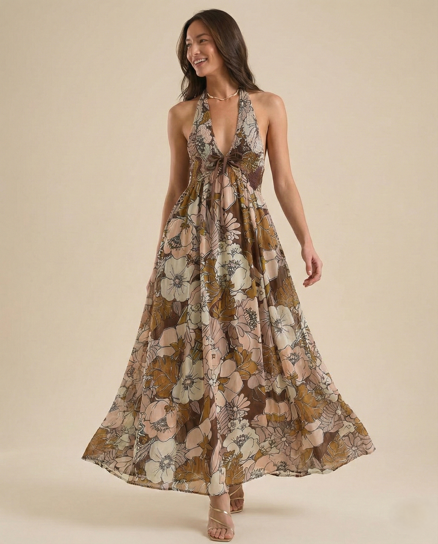 Autumn - A woman wearing a pastel floral print chiffon maxi dress with a smocked halter bodice, tie-neck detail, and a flowing skirt with a side slit.