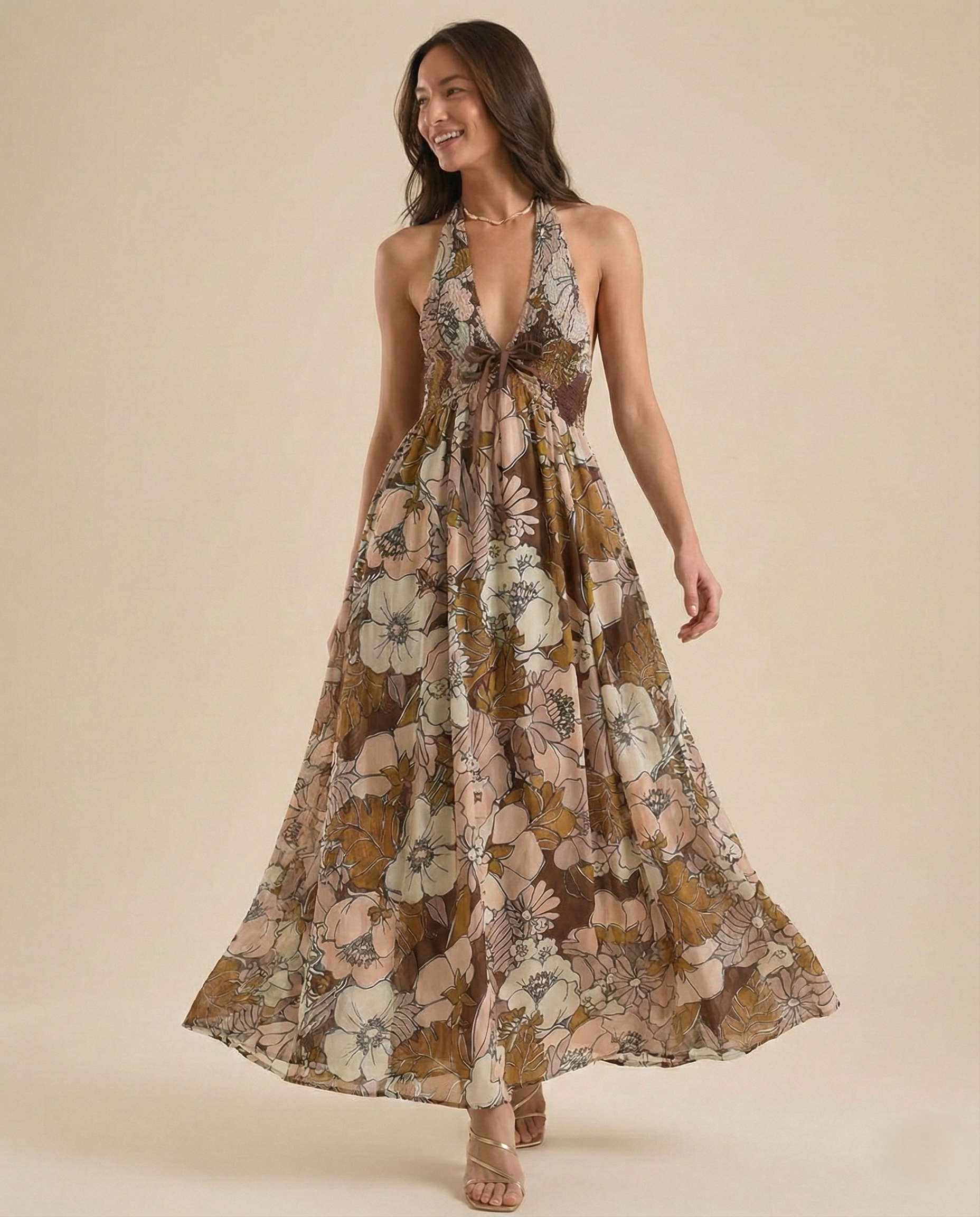 Autumn - A woman wearing a pastel floral print chiffon maxi dress with a smocked halter bodice, tie-neck detail, and a flowing skirt with a side slit.