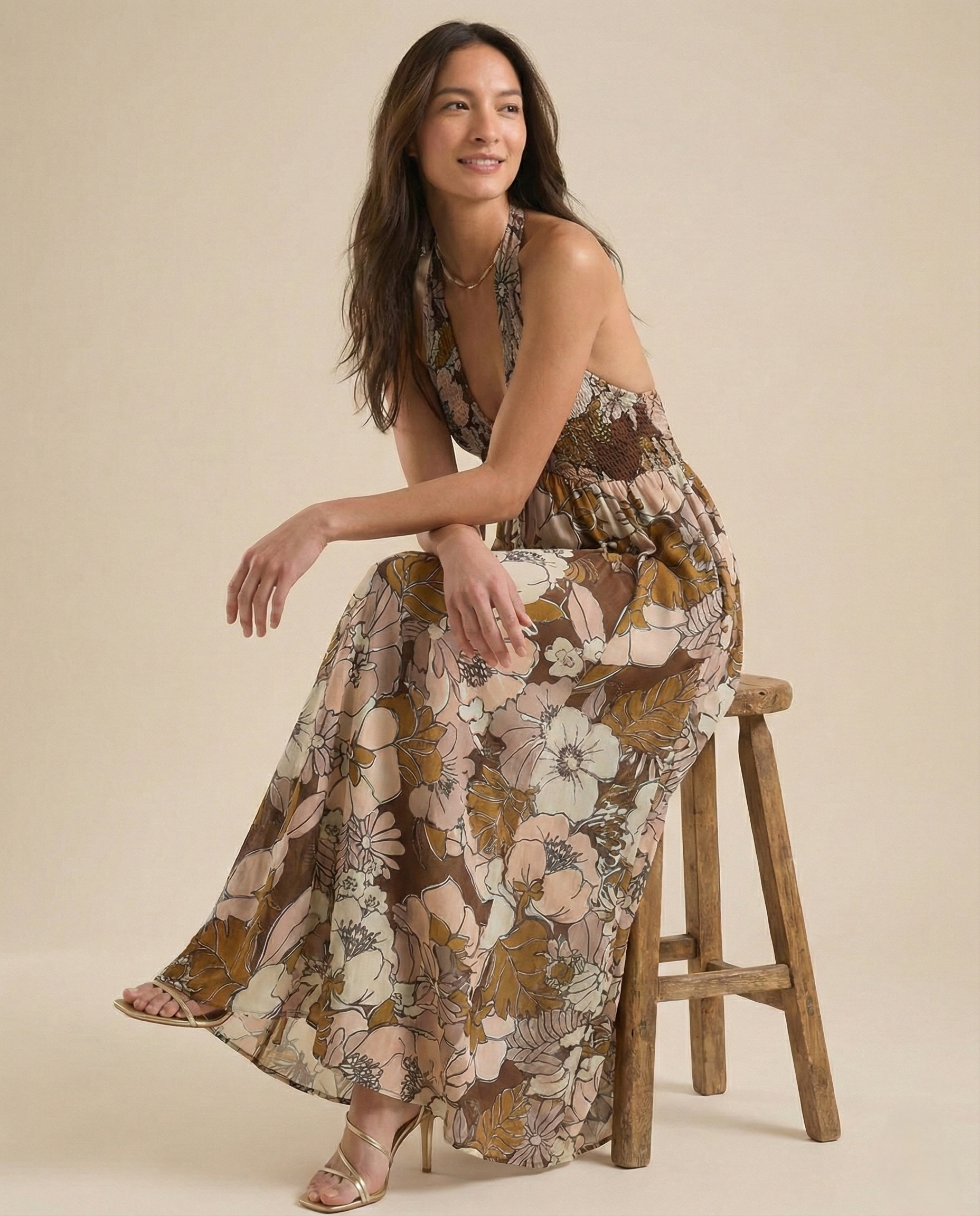 Autumn - A woman wearing a pastel floral print chiffon maxi dress with a smocked halter bodice, tie-neck detail, and a flowing skirt with a side slit.