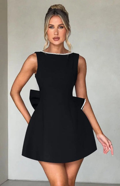 Black - Sleeveless crepe mini dress featuring a pearl-embellished bateau neckline, tailored princess seams, and a large structured back bow.