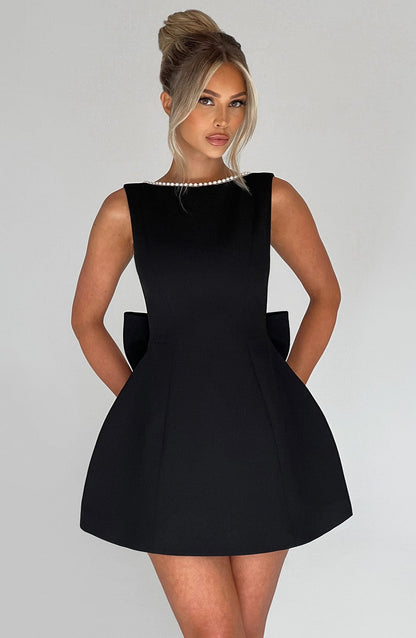 Black - Sleeveless crepe mini dress featuring a pearl-embellished bateau neckline, tailored princess seams, and a large structured back bow.