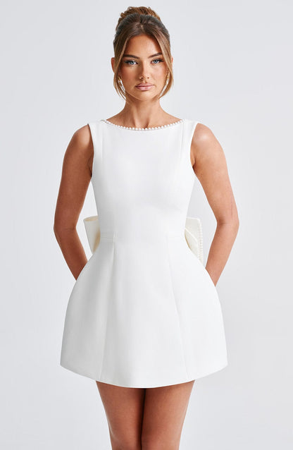Black - Sleeveless crepe mini dress featuring a pearl-embellished bateau neckline, tailored princess seams, and a large structured back bow.