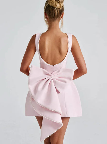 Black - Sleeveless crepe mini dress featuring a pearl-embellished bateau neckline, tailored princess seams, and a large structured back bow.