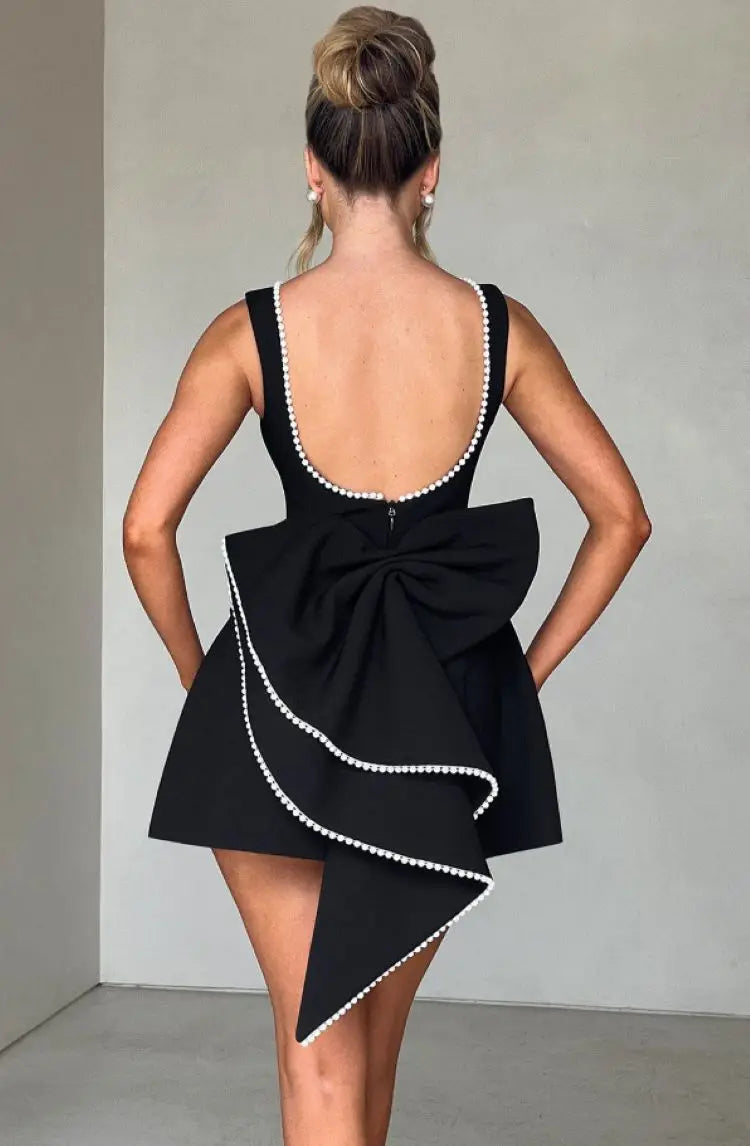 Black - Sleeveless crepe mini dress featuring a pearl-embellished bateau neckline, tailored princess seams, and a large structured back bow.