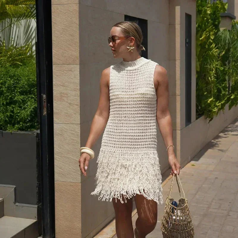 sand - Sleeveless crochet mini dress featuring a high mock neckline and a textured fringed hem.