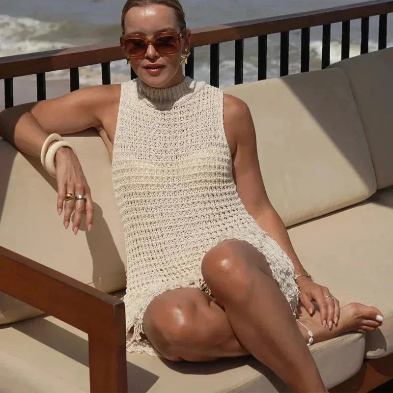 sand - Sleeveless crochet mini dress featuring a high mock neckline and a textured fringed hem.