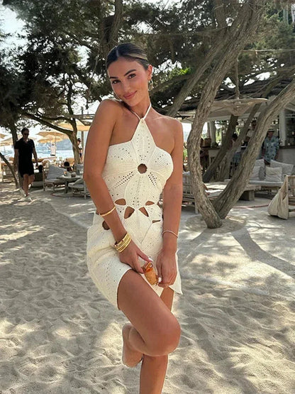 White - White crochet halter mini dress featuring large botanical cutouts, an asymmetrical hem, and an open waist design.