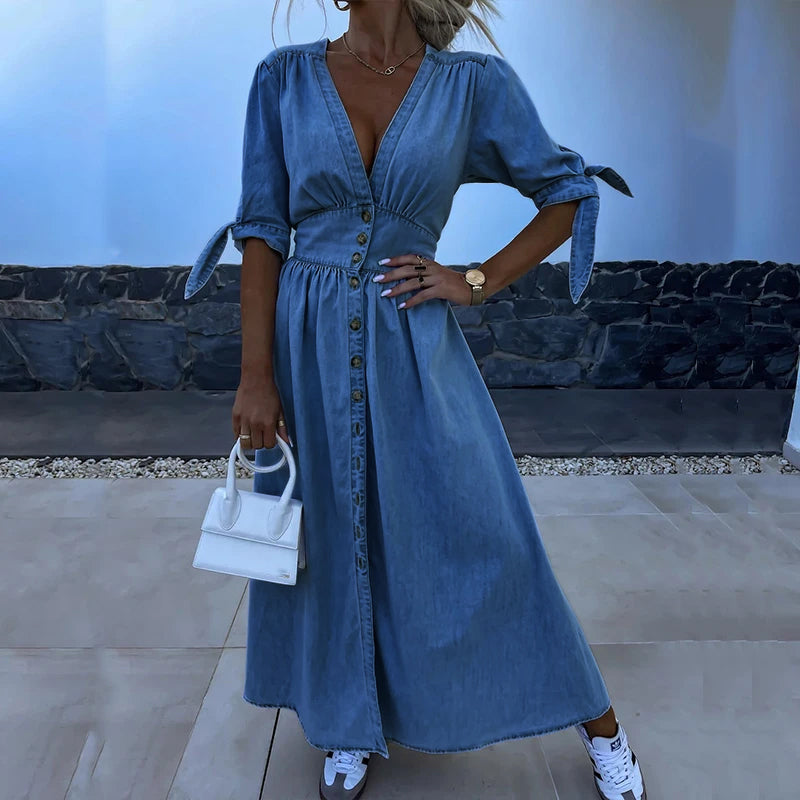 Blue - Light blue denim A-line maxi dress featuring a plunging V-neckline, button-front closure, banded waist, and short sleeves with tie cuffs.