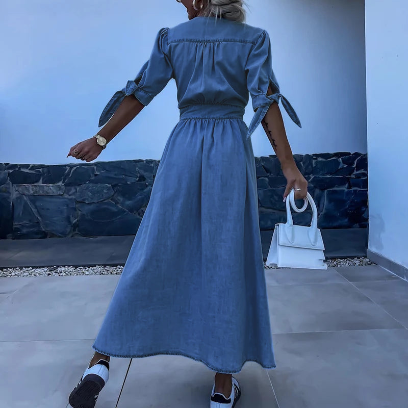Blue - Light blue denim A-line maxi dress featuring a plunging V-neckline, button-front closure, banded waist, and short sleeves with tie cuffs.