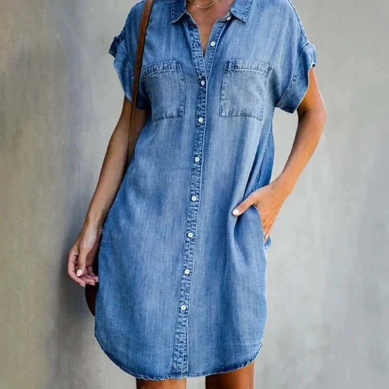 Light wash denim short-sleeve mini shirt dress featuring a collared neckline, button-front closure, dual chest pockets, and a curved hem.